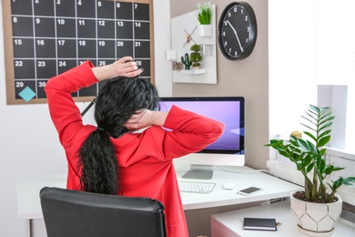 Photo of Young woman working with computer at desk in office