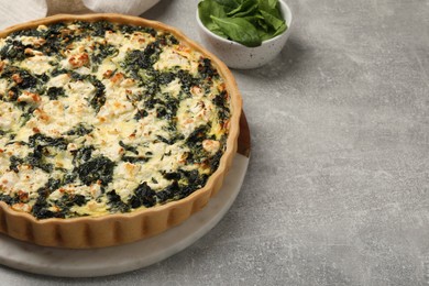 Delicious homemade spinach quiche on light gray table, closeup. Space for text