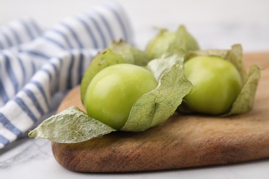 Photo of Fresh green tomatillos with husk on light table, closeup