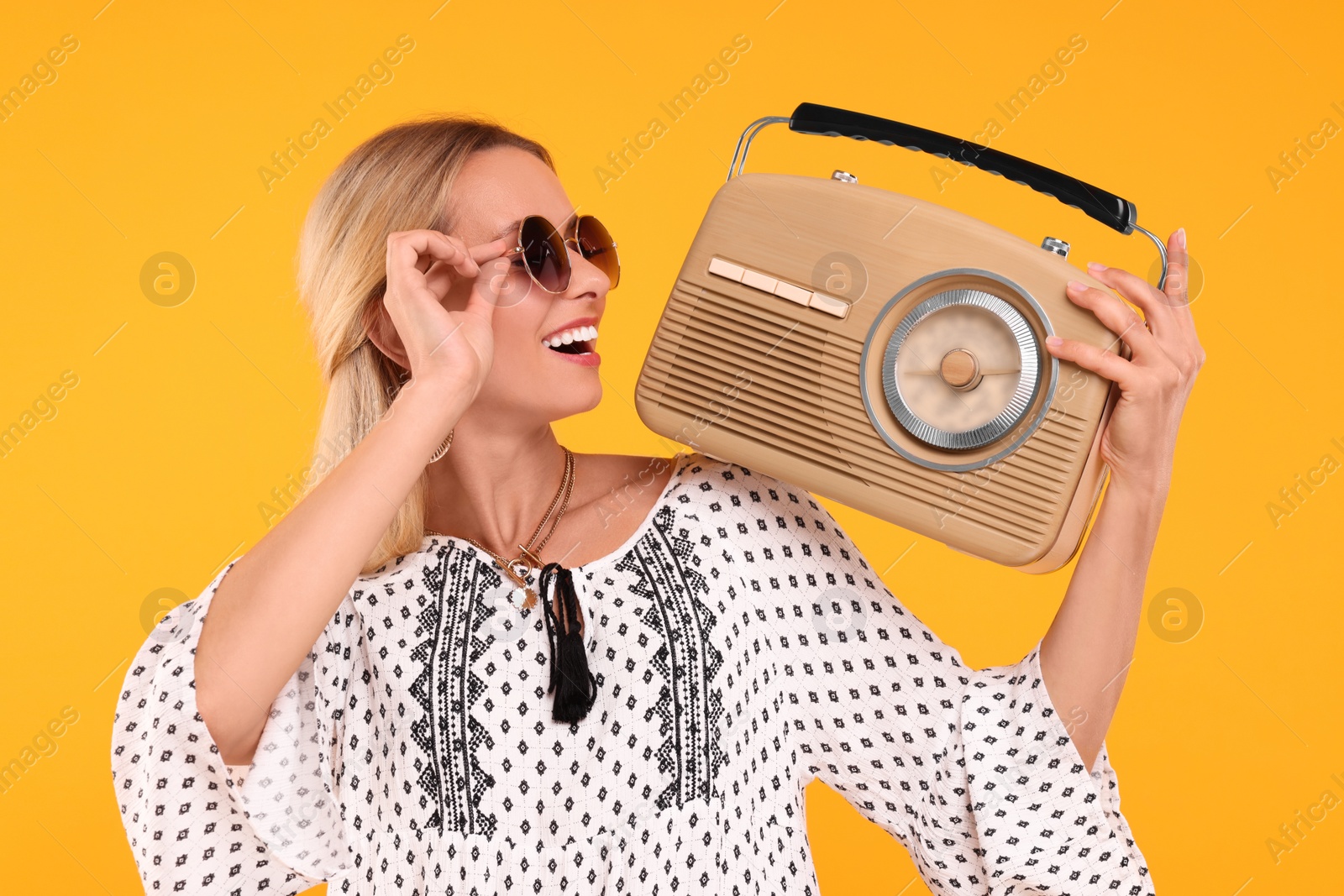 Photo of Portrait of happy hippie woman with retro radio receiver on yellow background