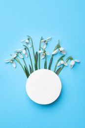Photo of Beautiful snowdrops and paper card on light blue background, flat lay. Space for text