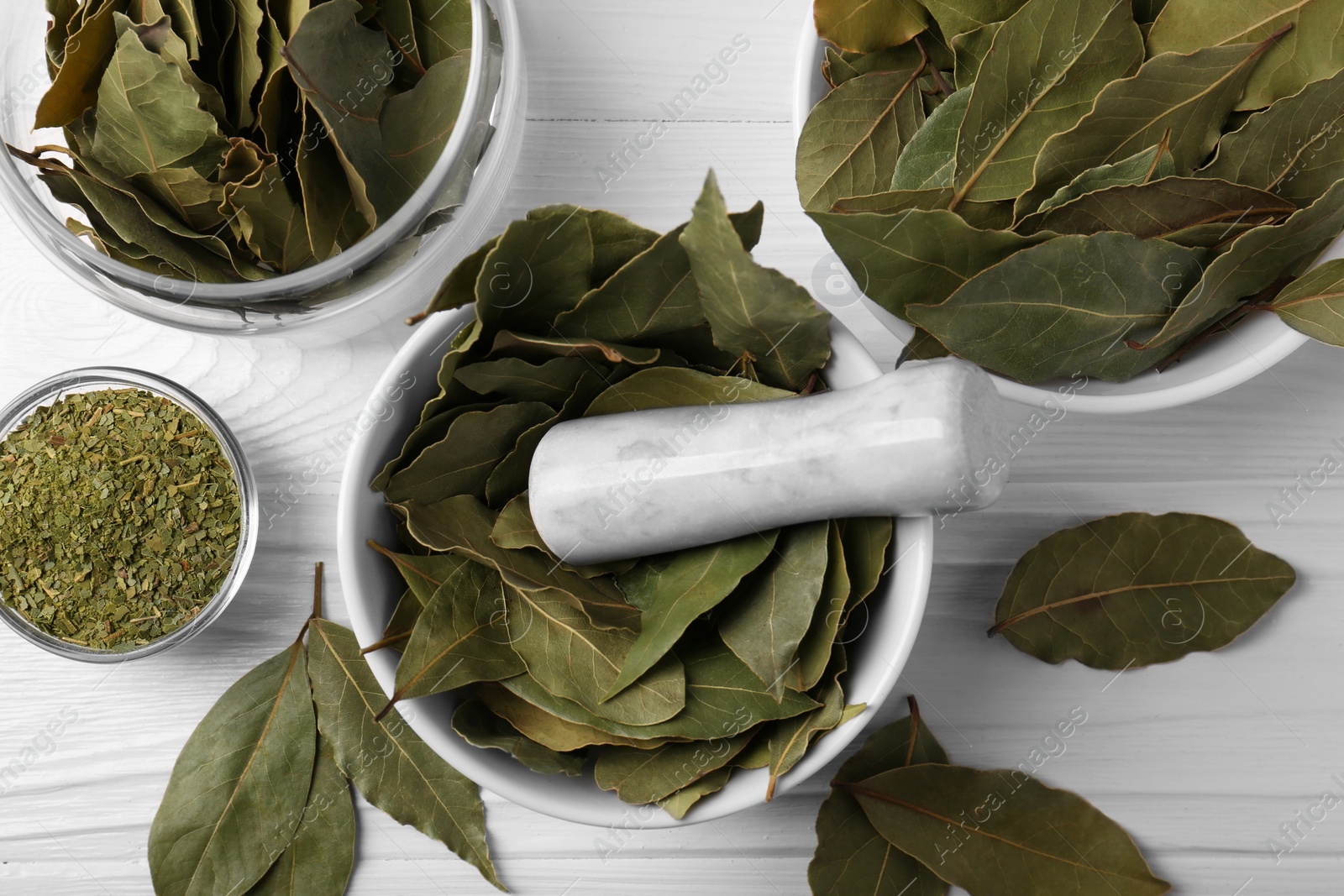 Photo of Whole and ground bay leaves on white wooden table, flat lay