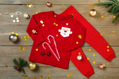 Flat lay composition with cute Christmas baby clothes on wooden background