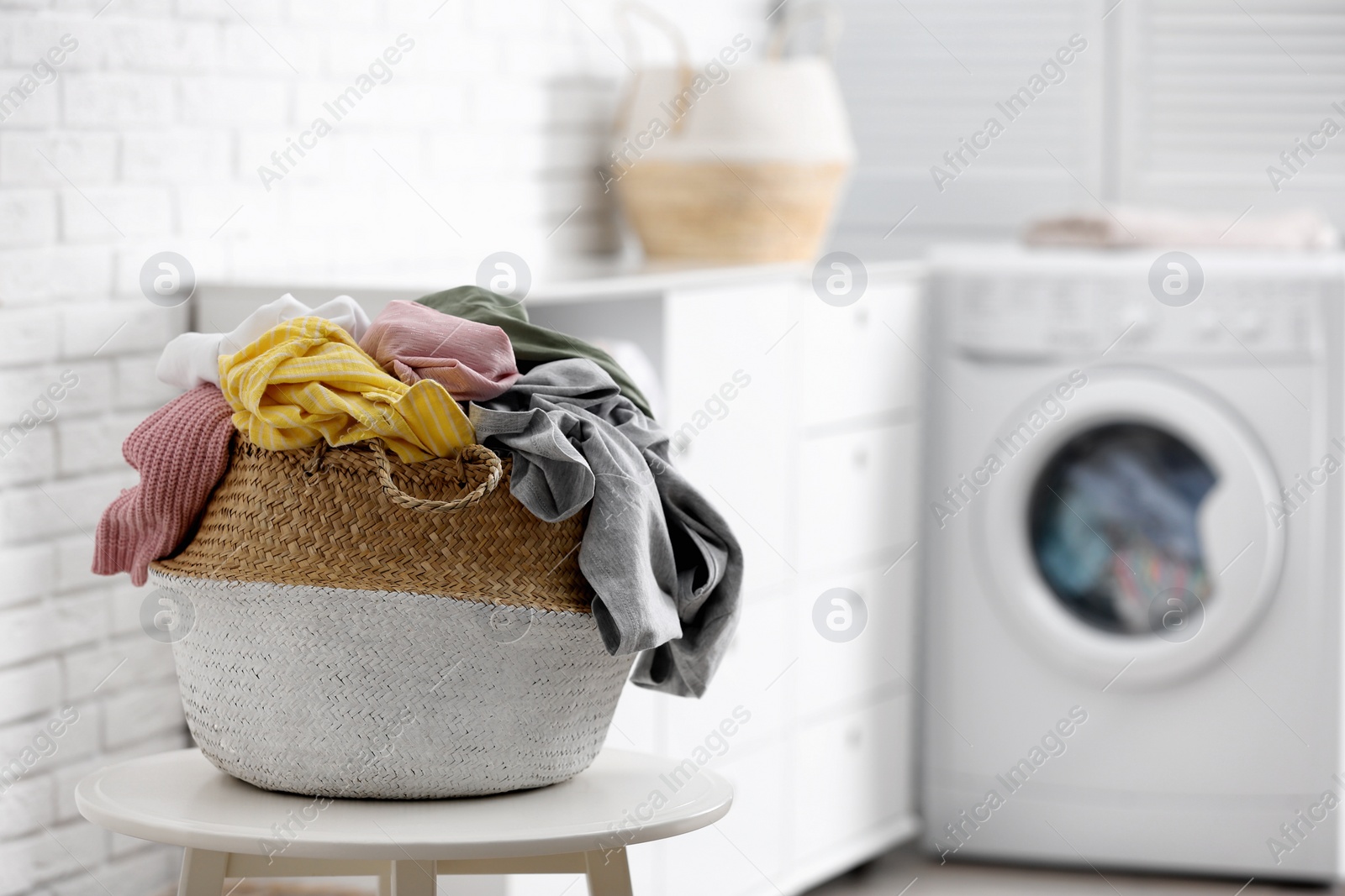 Photo of Wicker basket with dirty laundry indoors, space for text