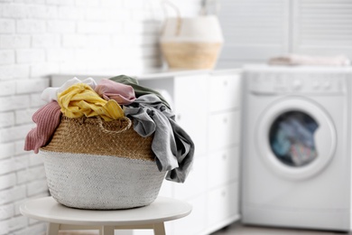 Photo of Wicker basket with dirty laundry indoors, space for text