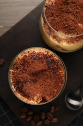 Photo of Delicious tiramisu in glasses and coffee beans on table, top view