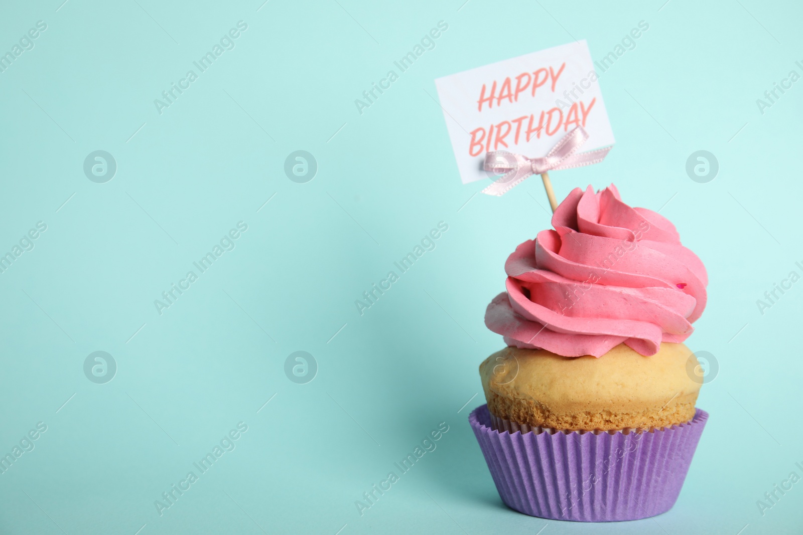 Photo of Beautiful birthday cupcake on light blue background. Space for text