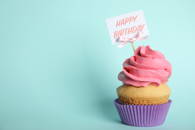 Photo of Beautiful birthday cupcake on light blue background. Space for text