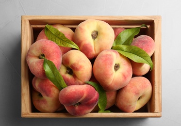 Photo of Fresh ripe donut peaches in crate on light table, top view