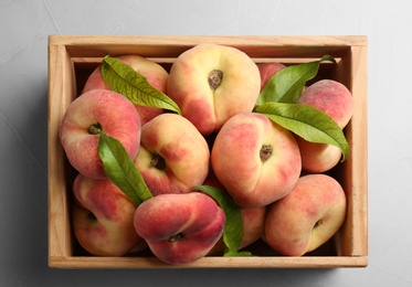 Fresh ripe donut peaches in crate on light table, top view