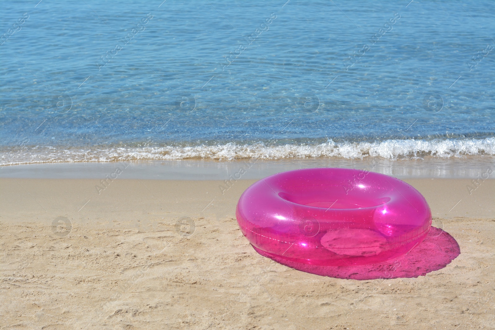 Photo of Bright inflatable ring on sandy beach near sea. Space for text