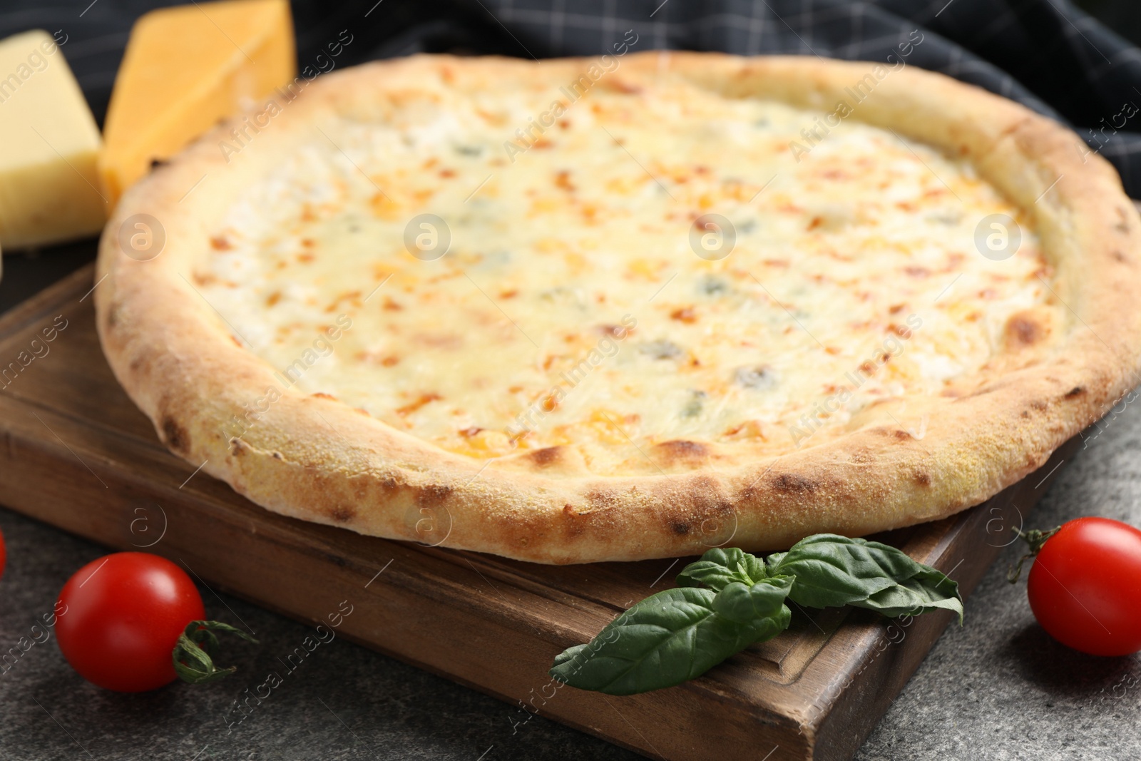 Photo of Delicious cheese pizza, basil and tomatoes on dark grey table, closeup