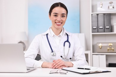 Medical consultant with stethoscope at table in clinic