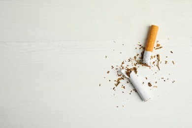 Photo of Broken cigarette on white table, flat lay with space for text. Quitting smoking concept