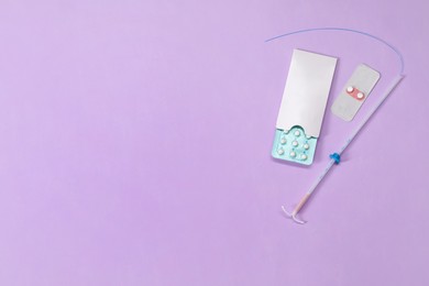 Photo of Contraception choice. Pills and intrauterine device on violet background, flat lay. Space for text