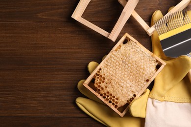 Photo of Honeycomb frames and beekeeping tools on wooden table, flat lay. Space for text
