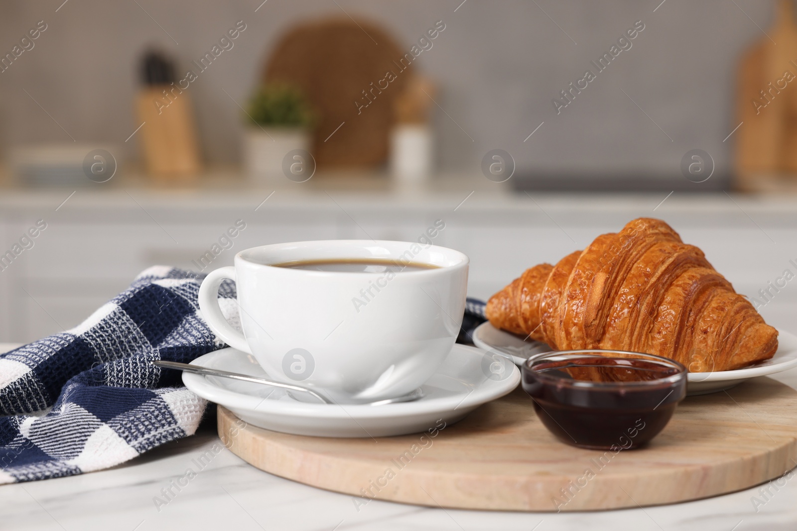 Photo of Breakfast served in kitchen. Fresh croissant, coffee, and jam on white table