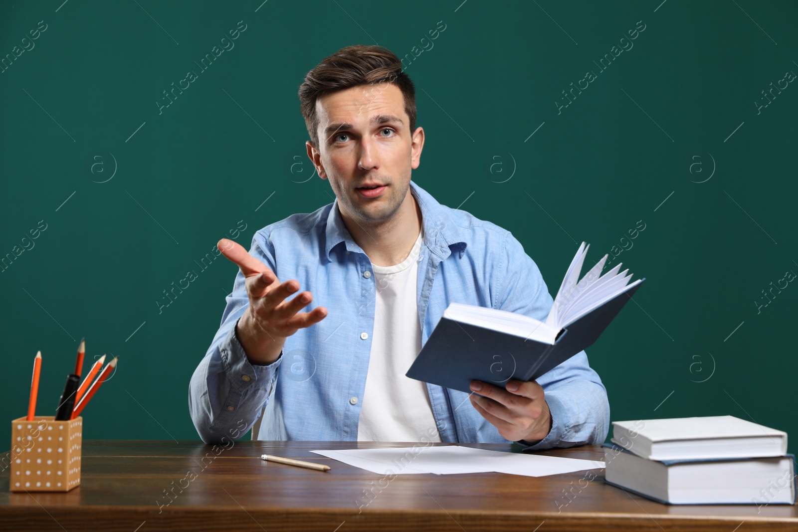 Photo of Portrait of male teacher working at table against color background