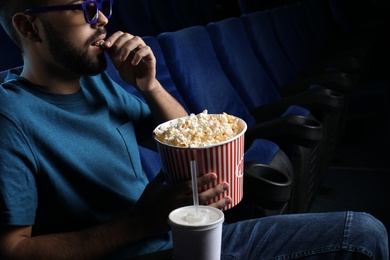 Young man with popcorn watching movie in cinema, closeup