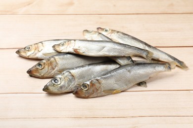 Photo of Fresh raw sprats on light wooden table, closeup