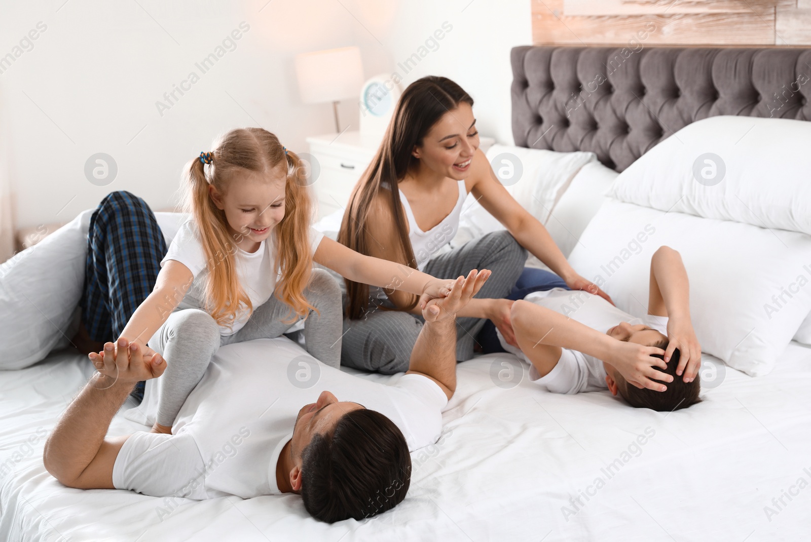 Photo of Happy young family together on large bed