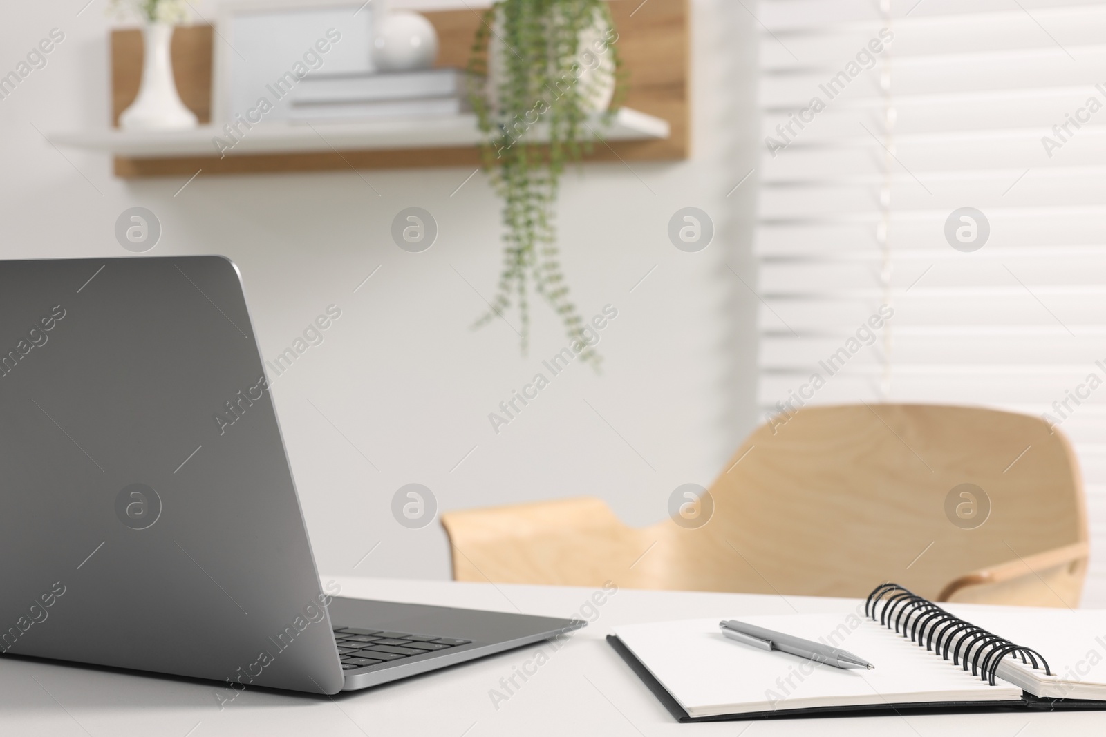 Photo of Home office. Laptop, notebook and pen on white desk indoors. Space for text