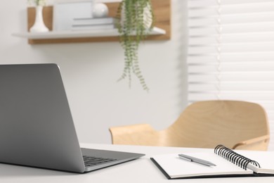 Home office. Laptop, notebook and pen on white desk indoors. Space for text