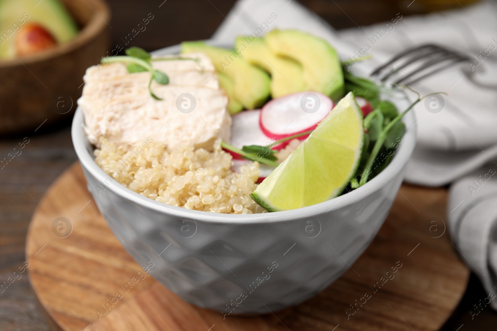 Photo of Delicious quinoa salad with chicken, avocado and radish served on table, closeup