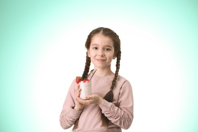 Photo of Cute girl eating tasty yogurt on color background