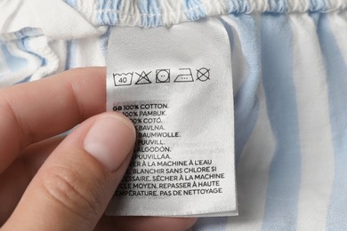 Photo of Woman holding clothing label on striped garment, closeup