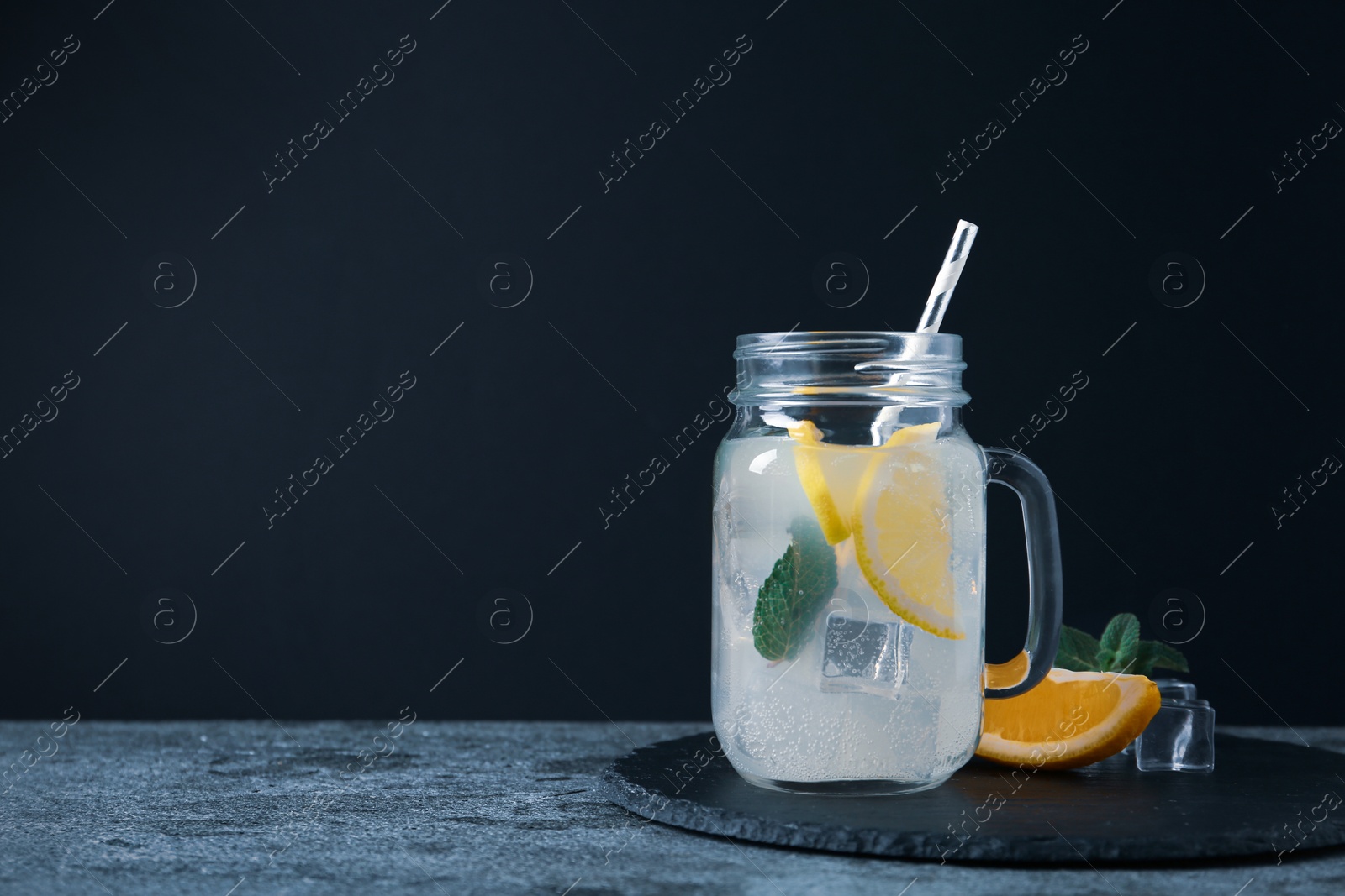 Photo of Delicious lemonade in mason jar on grey table. Space for text