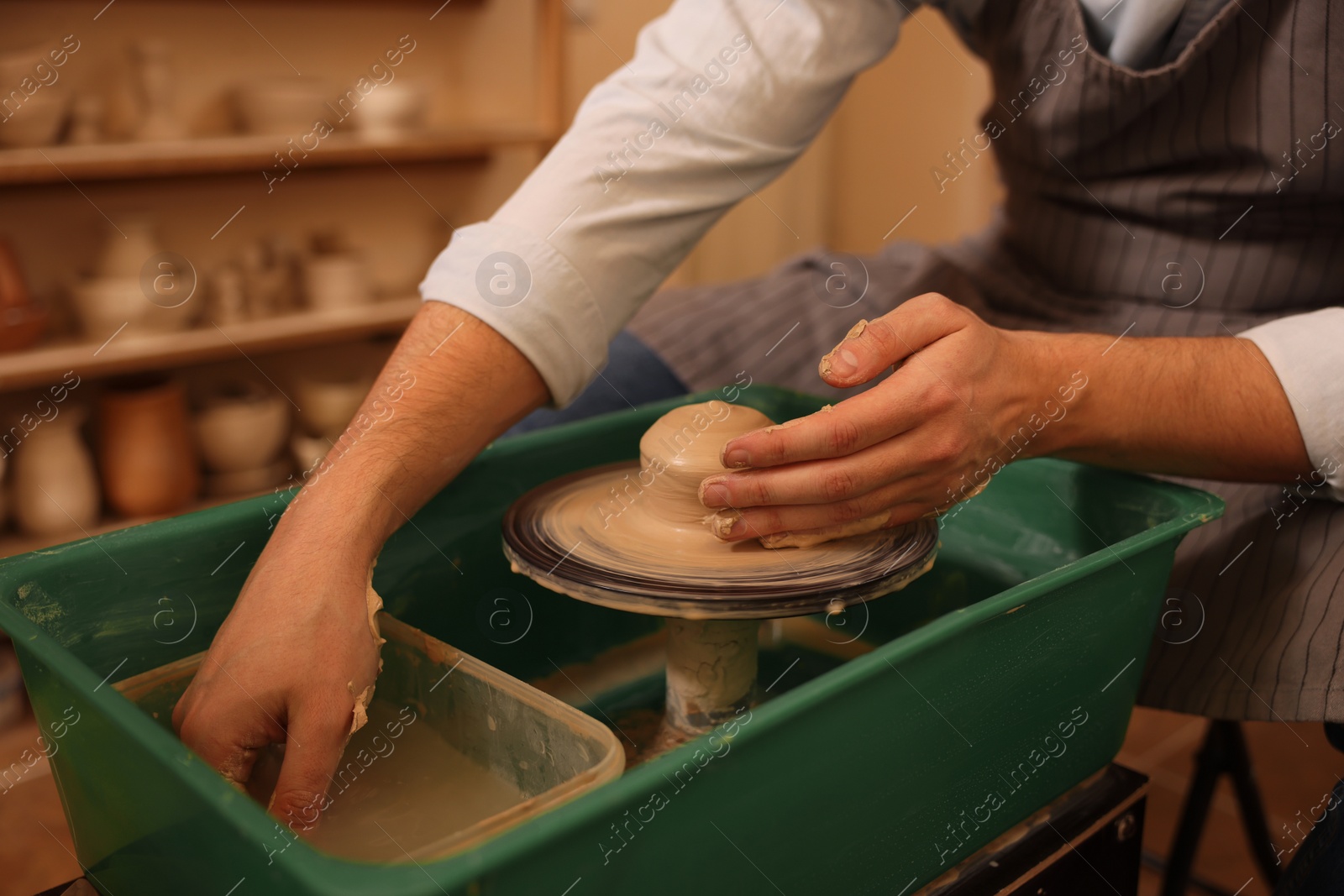 Photo of Man crafting with clay on potter's wheel indoors, closeup