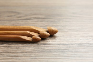 Photo of Three crochet hooks on wooden table, closeup. Space for text
