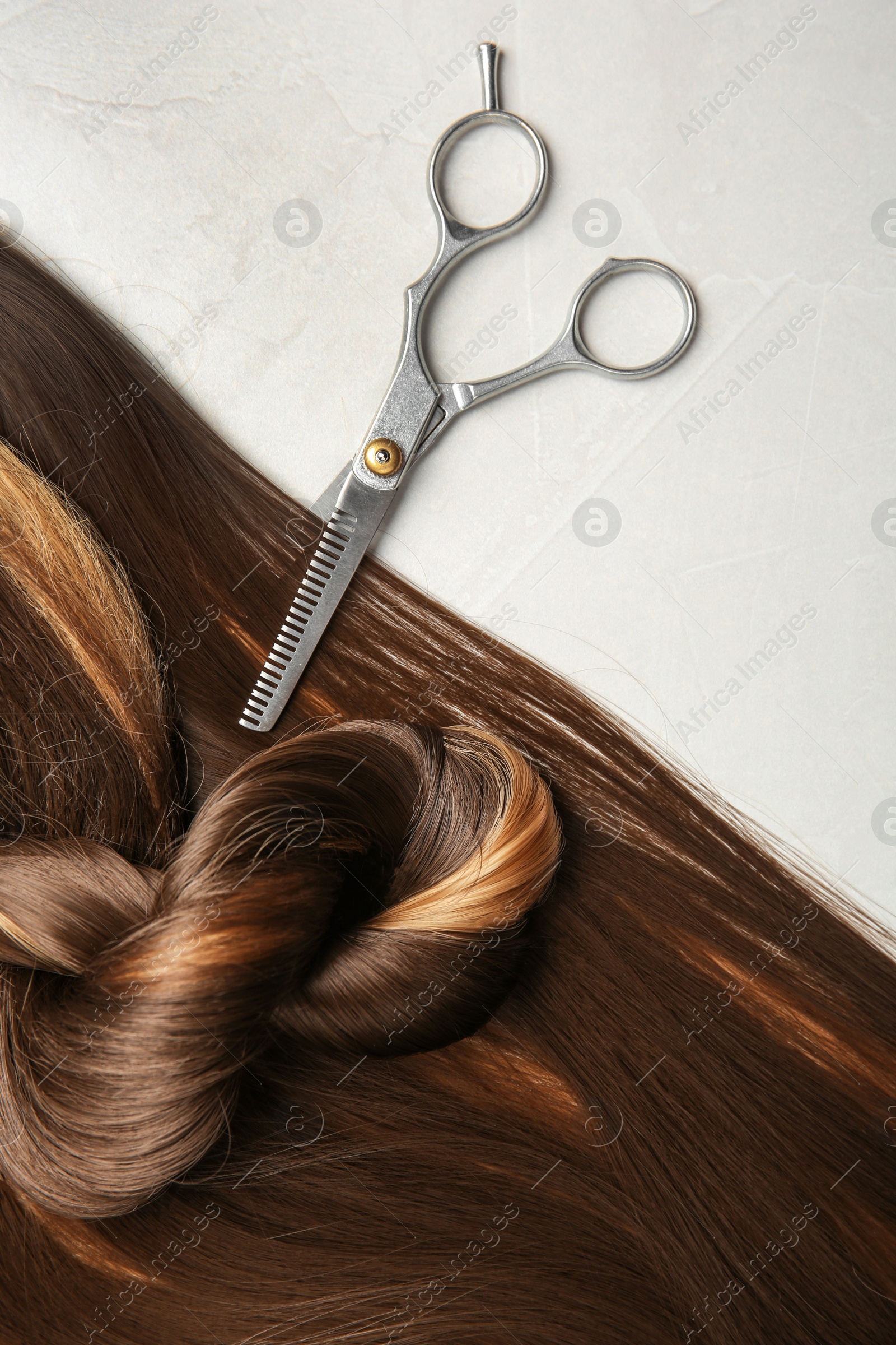 Photo of Flat lay composition with brown hair and scissors on gray background