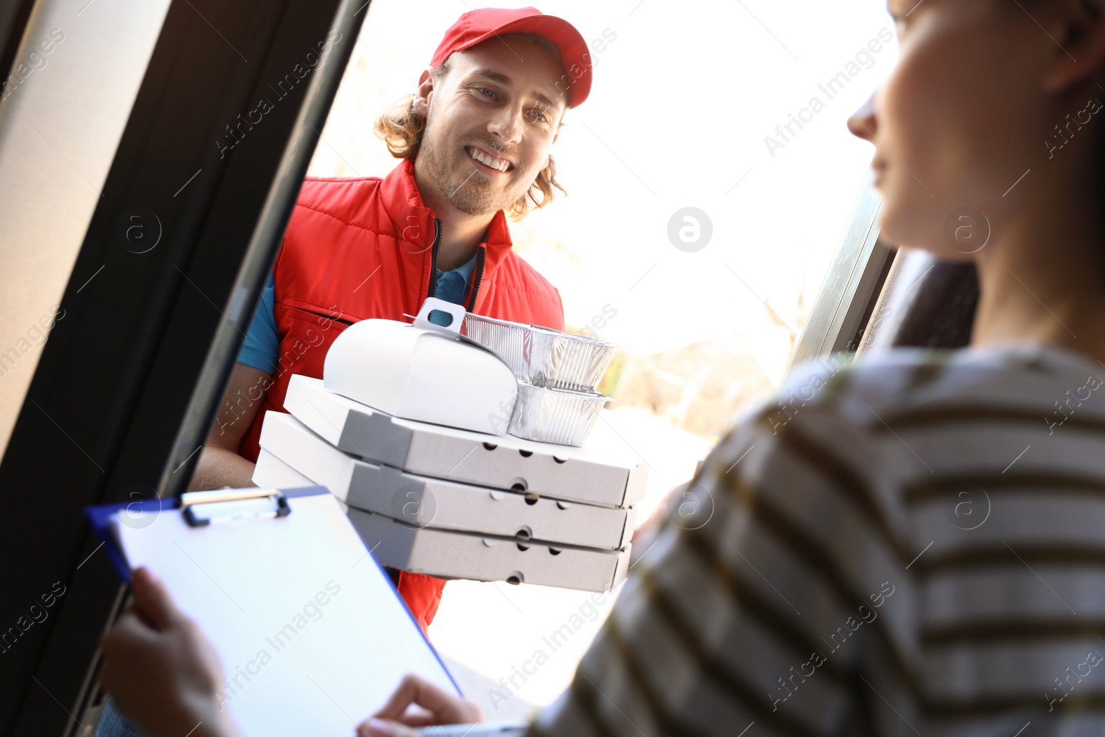Photo of Woman receiving order from courier at door. Food delivery service