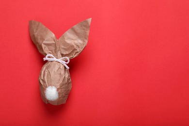 Photo of Easter bunny made of kraft paper on red background, top view. Space for text