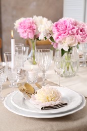 Photo of Stylish table setting with beautiful peonies and burning candle indoors
