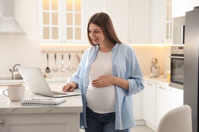 Photo of Pregnant woman working in kitchen at home. Maternity leave