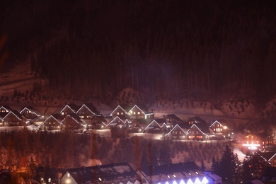 Photo of Night landscape with mountain village near forest in winter