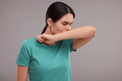 Photo of Woman coughing on grey background. Cold symptoms