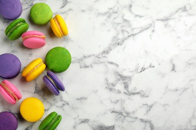 Photo of Delicious colorful macarons on white marble table, flat lay. Space for text