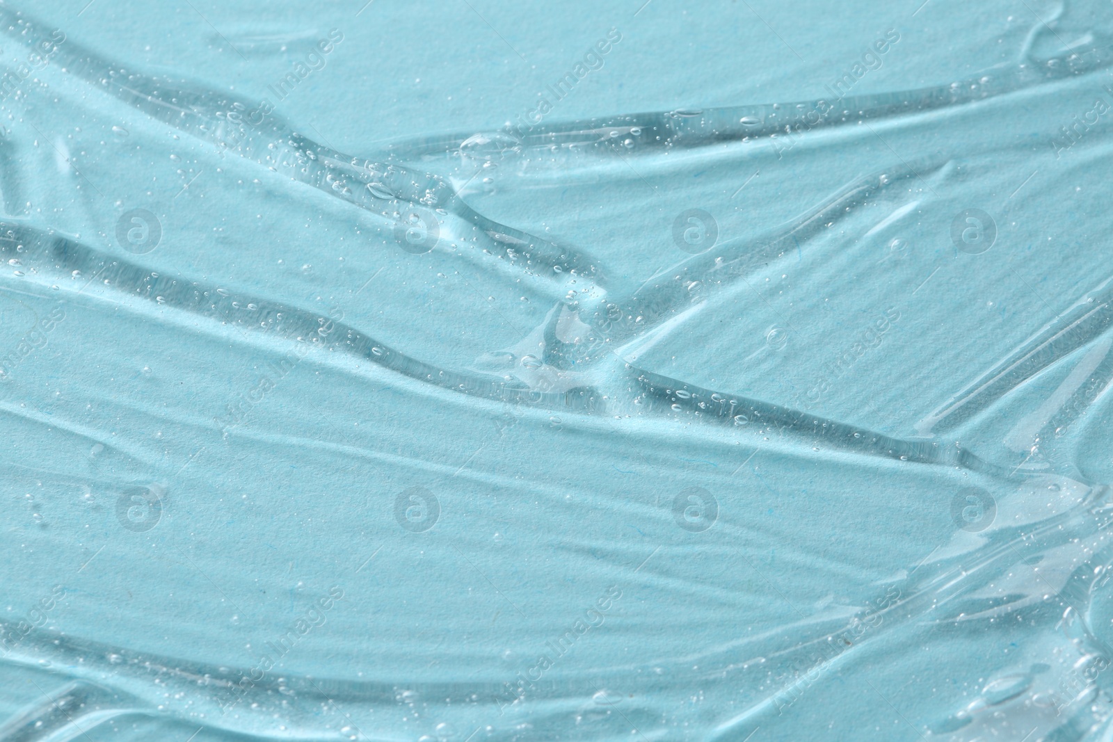 Photo of Clear cosmetic serum on light blue background, macro view