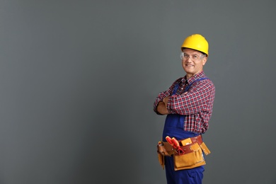 Photo of Electrician with tools wearing uniform on gray background. Space for text