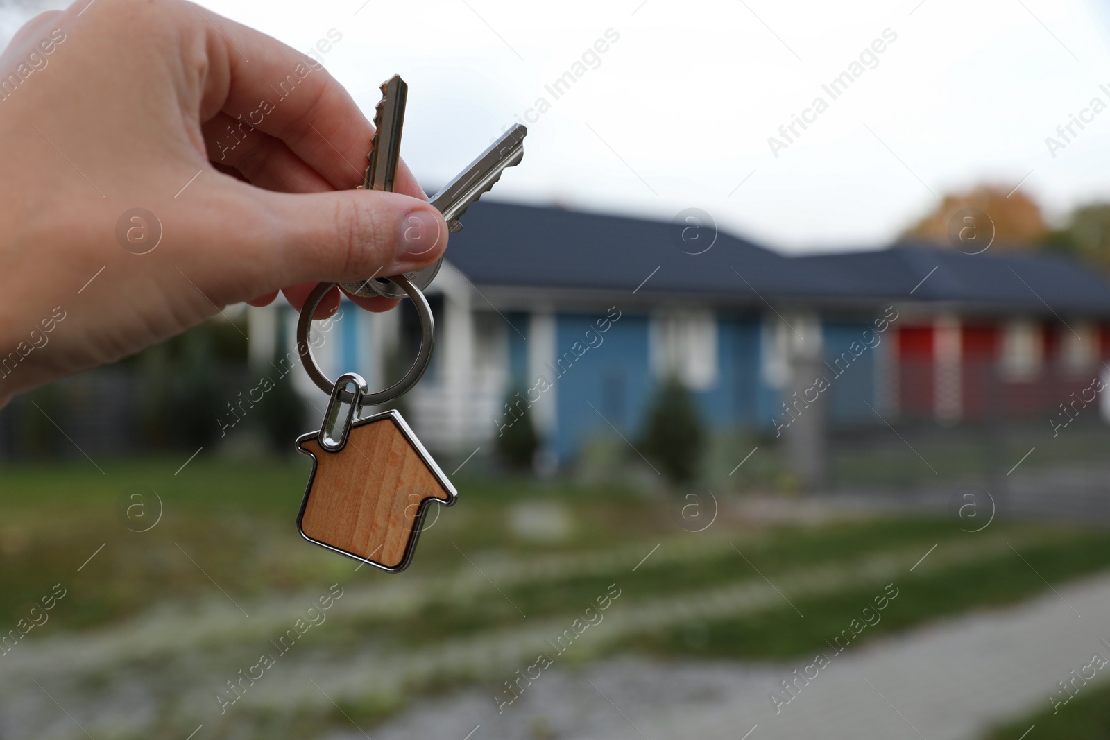 Photo of Woman holding house keys outdoors, closeup with space for text. Real estate agent