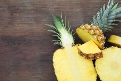 Photo of Cut ripe pineapples on wooden table, flat lay. Space for text