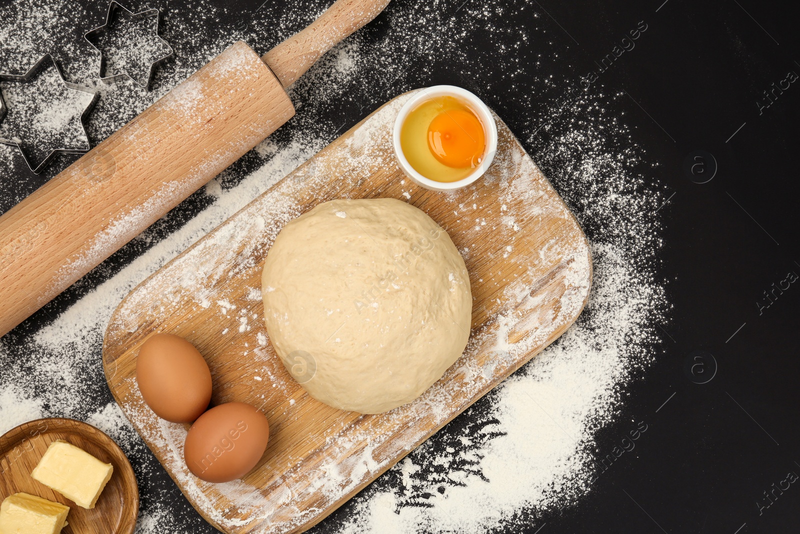 Photo of Flat lay composition with dough and other ingredients on black table. Baking pie