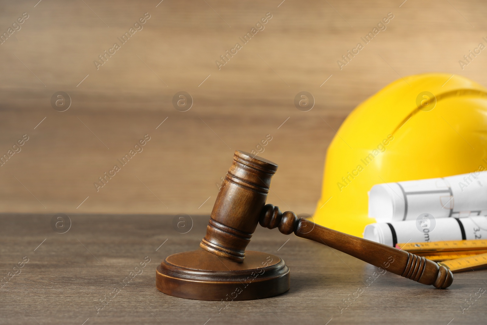 Photo of Construction and land law concepts. Judge gavel, protective helmet with drawings on wooden table, space for text