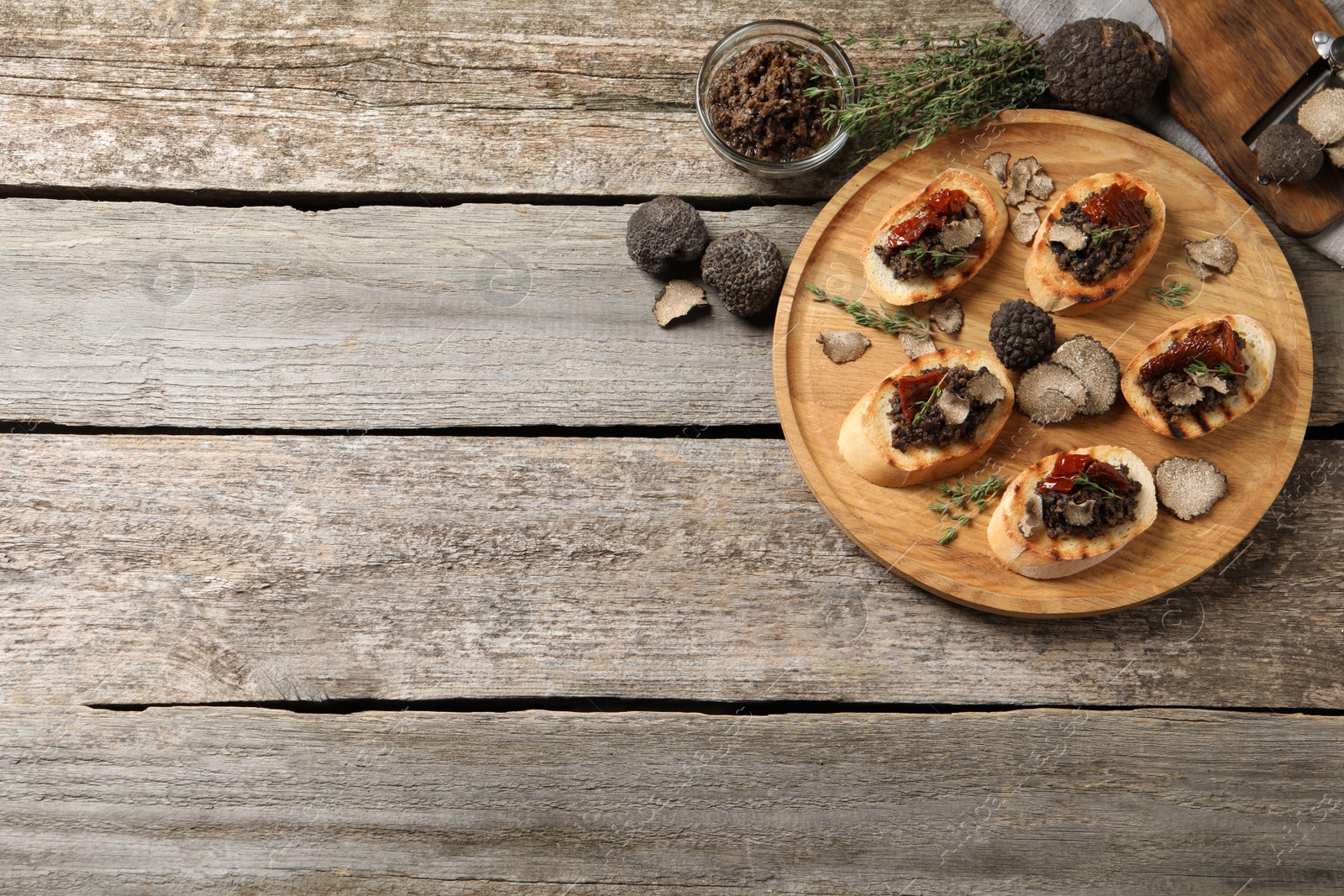 Photo of Delicious bruschettas with truffle sauce and sun dried tomatoes on wooden table, flat lay. Space for text
