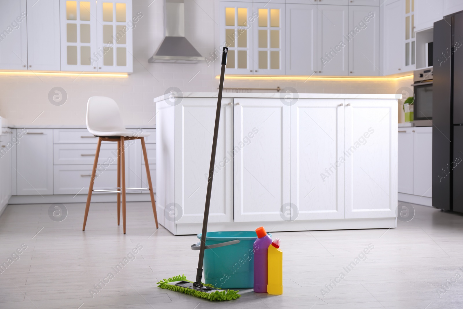Photo of Floor mop, bucket and cleaning products in kitchen