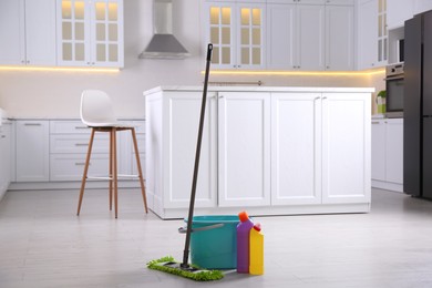 Floor mop, bucket and cleaning products in kitchen